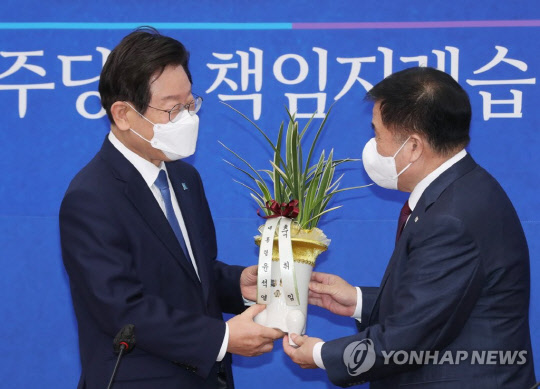 이재명 더불어민주당 신임 당대표가 30일 오전 서울 여의도 국회 대표실을 방문한 이진복 대통령실 정무수석으로부터 축하난을 받고 있다.<연합뉴스>